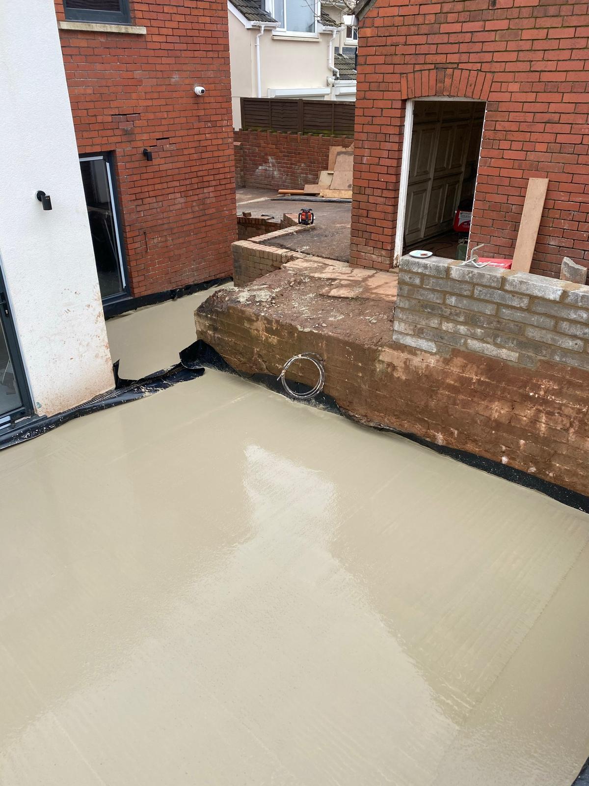 Freshly poured liquid flowing screed laid flat across a South Wales extension